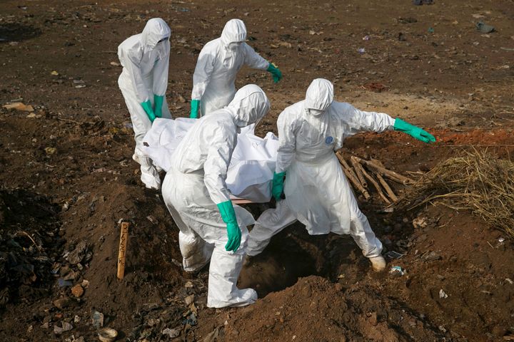 Health workers carry the body of a suspected Ebola victim for burial at a cemetery in Freetown, Sierra Leone, December 21, 2014.