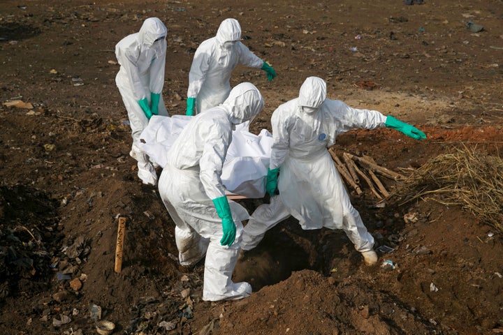 Health workers carry the body of a suspected Ebola victim for burial at a cemetery in Freetown, Sierra Leone, December 21, 2014.