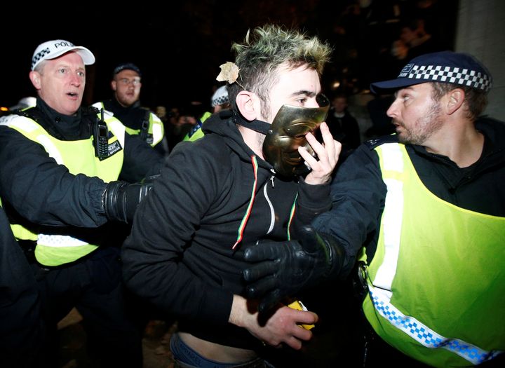 Police detain a protester during the Million Mask March in London