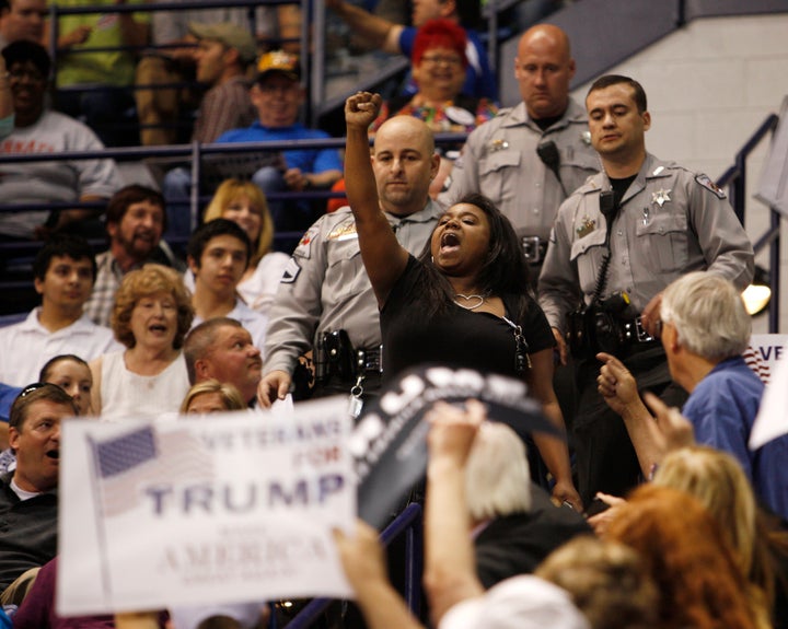 A black demonstrator raises her fist in protest against U.S. Republican presidential candidate Donald Trump as police officers approach to remove her from a campaign rally in Fayetteville, North Carolina, in March.