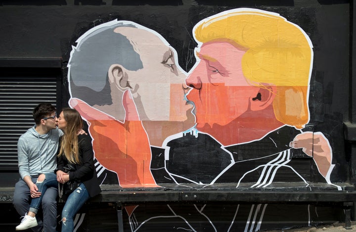 A couple kisses in front of graffiti depicting Russian President Vladimir Putin and Republican presidential nominee Dona