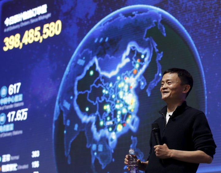 Alibaba founder and chairman Jack Ma gestures in front of a screen showing real-time data of transactions at Alibaba Group's