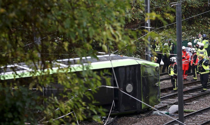 Members of the emergency services work next to a tram after it overturned injuring and trapping some passengers in Croydon, s