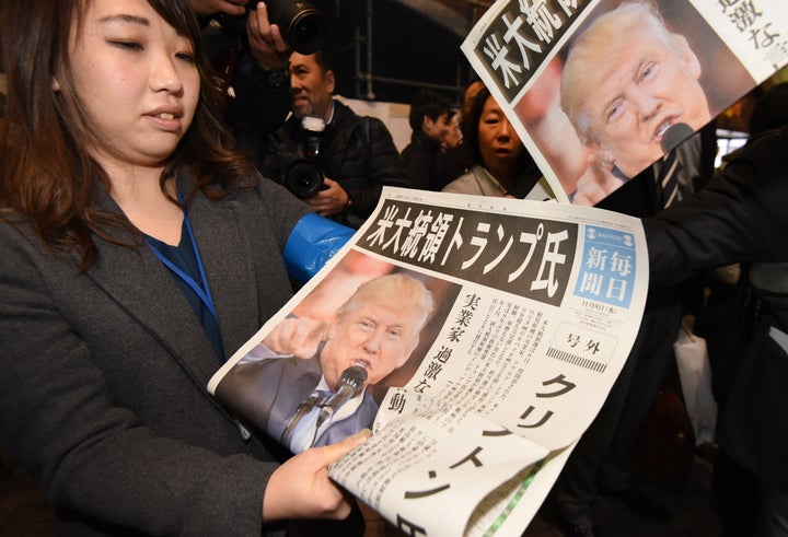 A woman gives out extra editions of a newspaper reporting Trump's victory. Tokyo, Nov. 9.