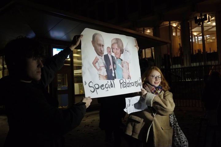 Protestors hold a sign showing Theresa May with Trump and Russian President Vladimir Putin