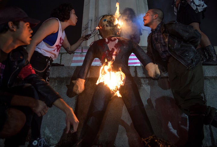 Protesters burn an effigy of Donald Trump in Lee Circle before a march through New Orleans