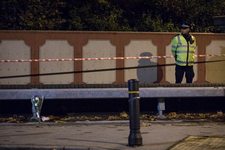 A police officer stands by floral tributes left for the victims of the derailed tram 