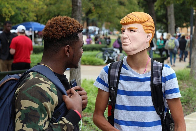 <p>UNT student Aquarius Dickens discussing with another student masked as Donald Trump</p>