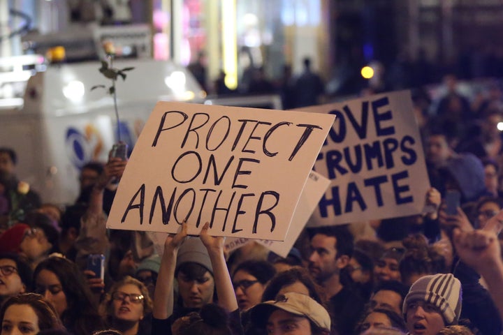 <strong>New York: A protestor holds a sign calling for people to 'protect one another'</strong>