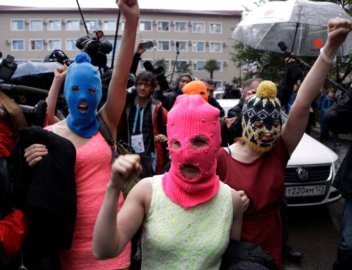 Russian punk group Pussy Riot members wearing pink and blue balaclava make their way through a crowd after they were released from a police station in February 2014 in Adler, Russia. No charges were filed.