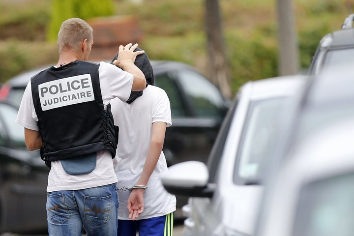 A French policeman arrests a man following a house raid on July 26, 2016 in Saint-Etienne-du-Rouvray, where two men who said they acted on behalf of ISIS killed a priest.