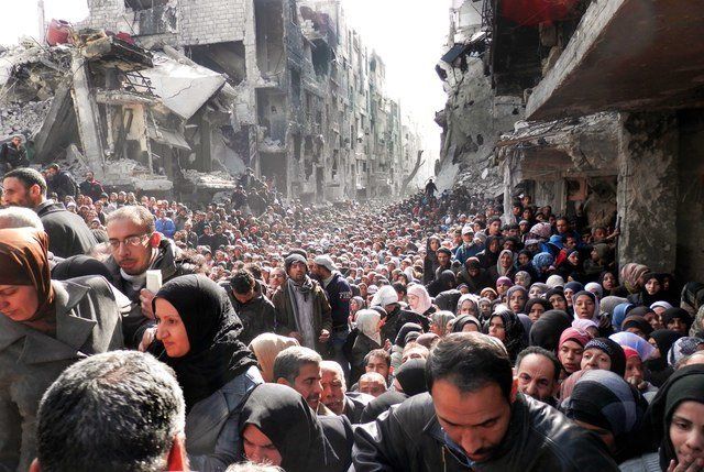 Residents of the besieged Palestinian camp of Yarmouk in Damascus, Syria, queue to receive food supplies.