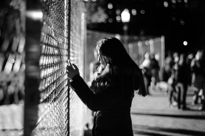 A woman texts and clutches the fence separating the White House and Lafayette Park on election night.