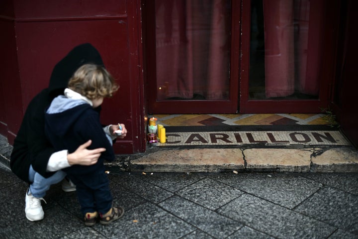 A woman with her child lays candles in tribute to the victims, outside Le Carillon restaurant near Rue Alibert and Rue Bichat in Paris.