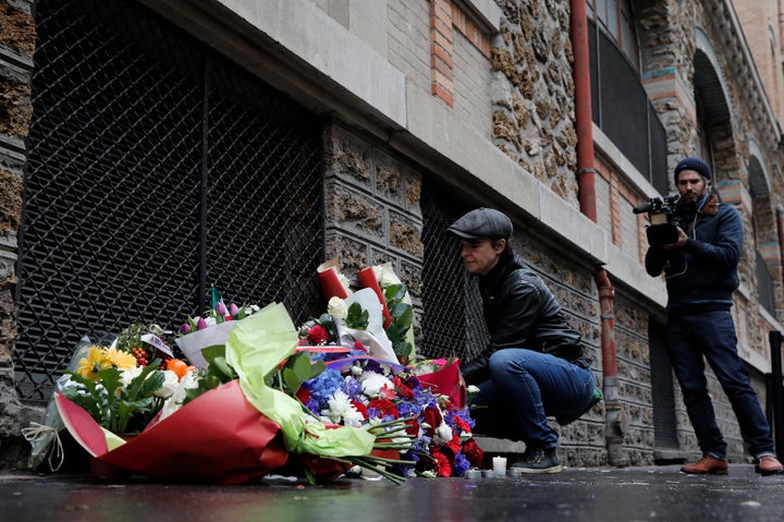 A woman pays her respects under a commemorative plaque next to the "La Belle Equipe" bar and restaurant, in Paris, France, November 13, 2016.