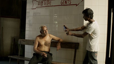 <p>Sheikh Rehman discusses painting with one of his assistants in a scene from <strong><em>Original Copy</em></strong> </p>