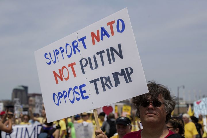 A protester holds a sign reading "Support NATO / Not Putin / Oppose Trump."