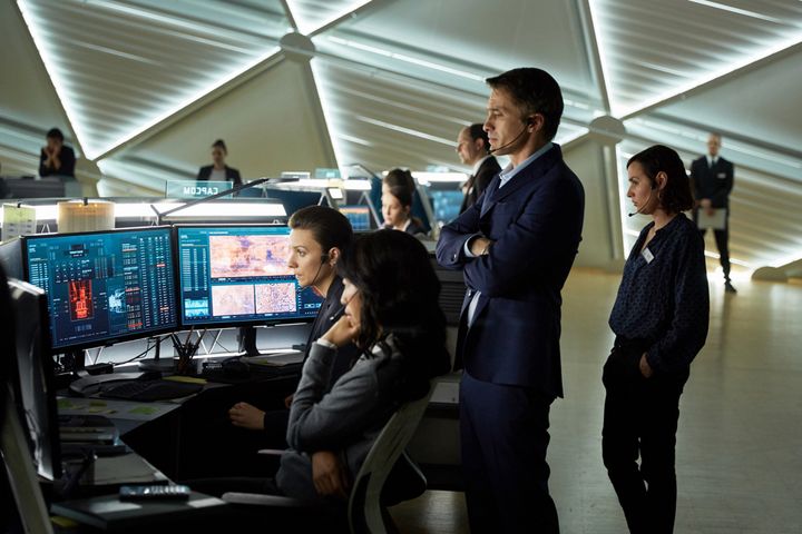 Olivier Martinez as Ed Grann the French CEO of the Mars Mission Corporation looks on over Jihae as Joon Seung the Korean-American capsule communicator.