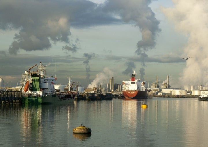 Ships berthed in the Port of Rotterdam with refineries and fuel storage tanks in the background.