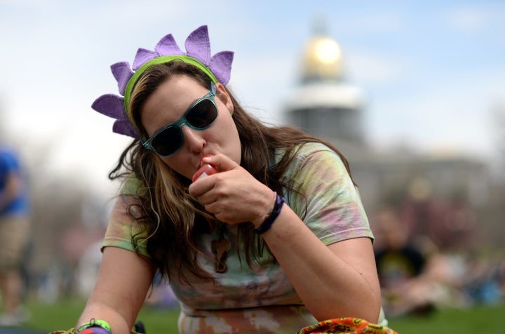 A young woman smokes marijuana during the 420 Rally weekend at the Civic Center Park in Denver, Colorado on April 19, 2014.