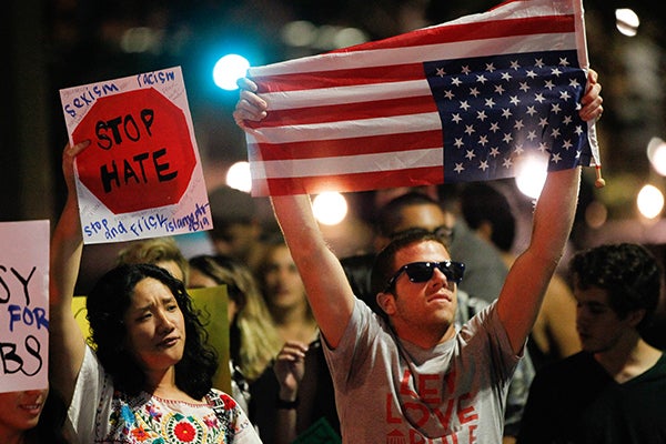 A man holds an American flag upside down in a sign of national distress on Wednesday, Nov. 9, 2016, in San Diego, at a protes