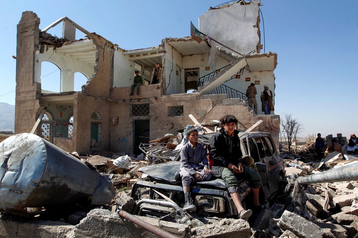 Children sit amidst the rubble of a house hit by Saudi-led coalition air strikes two days earlier on the outskirts of the Yem