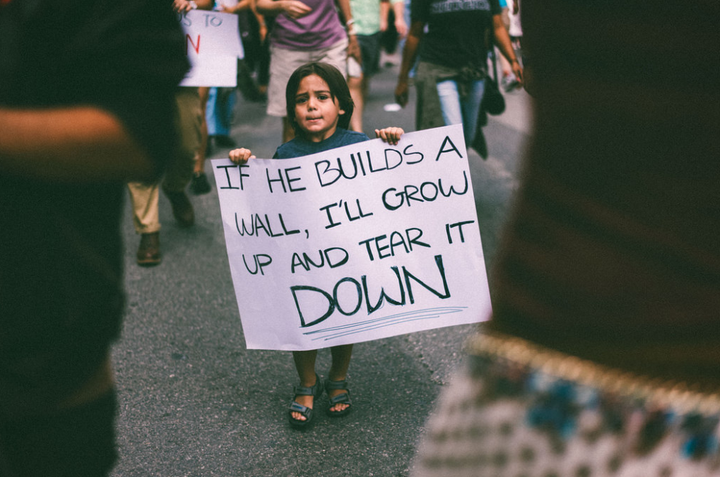 Kaio Pinho, 3, held this sign at an anti-Trump march on Saturday.