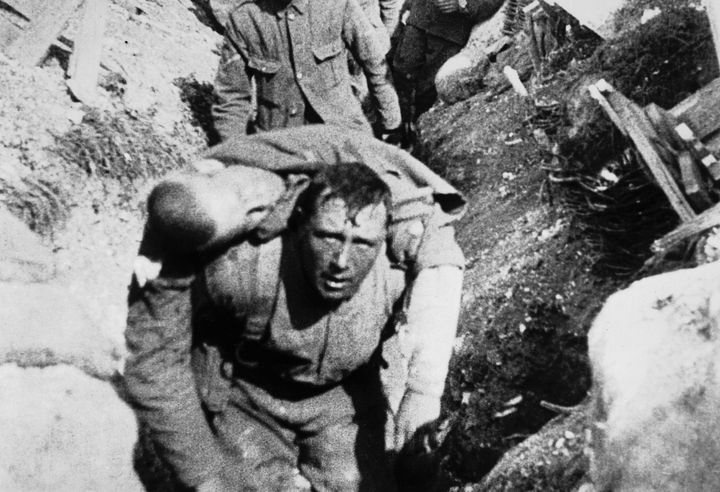 A soldier carries a wounded comrade through the trenches