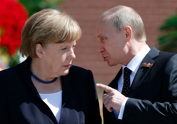 Russian President Vladimir Putin speaking with German Chancellor Angela Merkel at the Tomb of the Unknown Soldier by the Kremlin walls in Moscow, Russia, May 10, 2015.