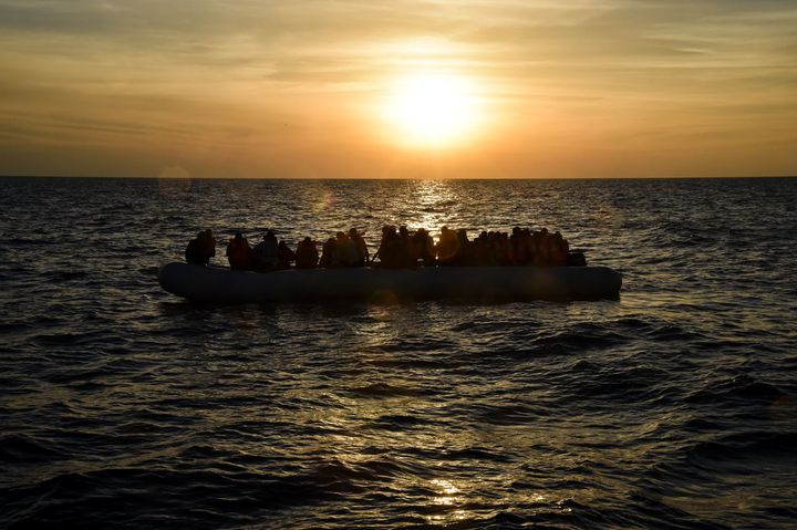 Migrants and refugees sit on a rubber boat in the Med earlier this month