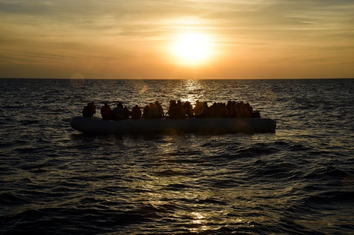 Migrants and refugees sit on a rubber boat in the Med earlier this month