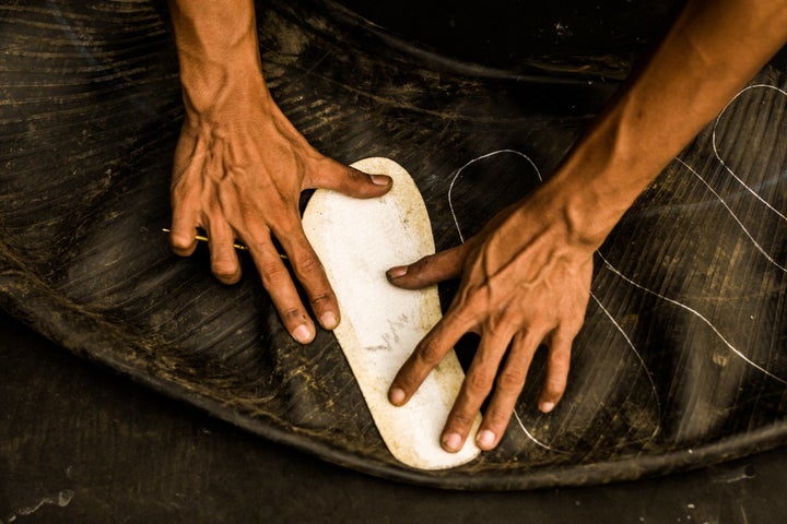 <p>An artisan traces the shape of a sole onto a tire inner tube.</p>