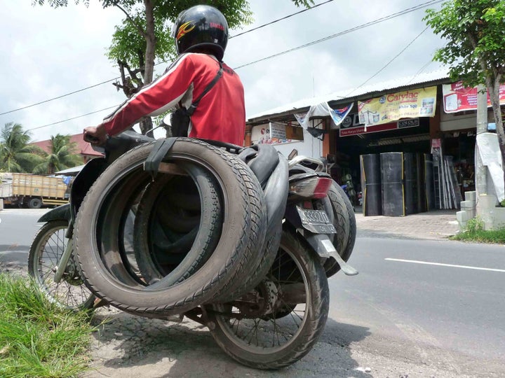 A man collects waste tires in Indonesia, most likely on his way to a tire broker.