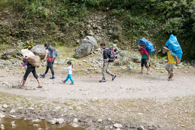 <em>Trekking in the Khumbu Valley, flanked by porters with loads up to 60kg. Porters earn between $10 — $15 per day carrying