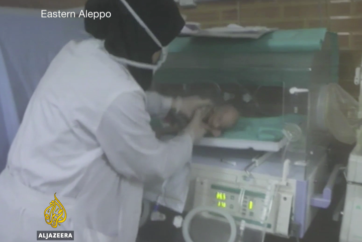 A nurse pulls a tiny baby from its incubator as bombs fall on the hospital 