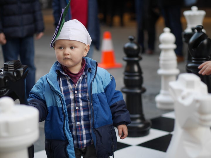 a young chess fan explores the life-size chessboard outside the playing venue