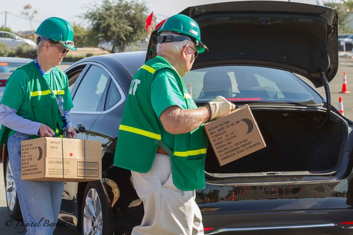 <p>Volunteer members of Community Emergency Response Teams (CERT) load boxes of food and water into the trunk of a waiting vehicle at a Commodities Point of Distribution (C-POD) site in Irvine</p>