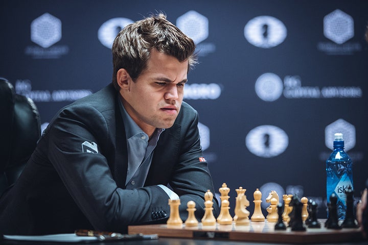 World chess champion Magnus Carlsen frowns at the board during his 8th game against challenger Sergey Karjakin