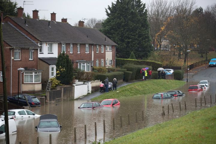 Residents look at cars that have been submerged under several feet of flood water in Hartcliffe yesterday.