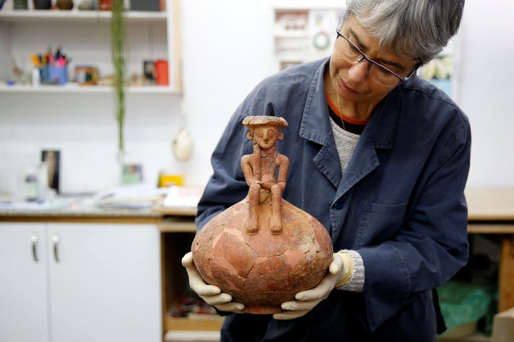 Conservationist Elisheva Kamaisky, shows journalists a 3,800 year-old pottery jug with a rare statuette, discovered during excavation in central Israel.