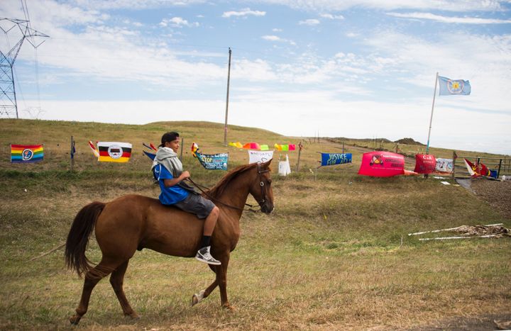 A youth rides a horse over a fenced area of land set aside for the Dakota Access Pipeline in North Dakota.