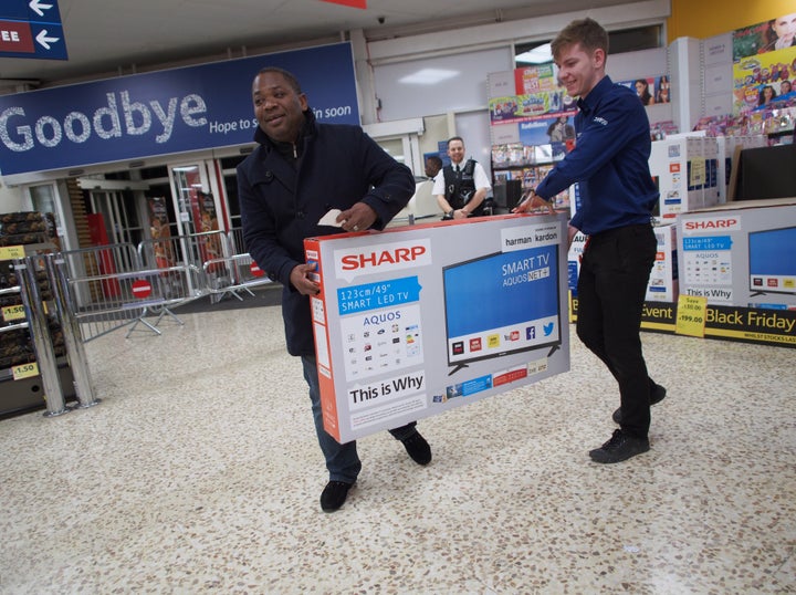 Customers shopping for bargains on Black Friday carry a flat screen TV at a Tesco Extra store in Ponders End, Enfield, north London