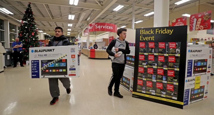 A shopper is pictured carrying a TV set out of a Tesco Extra store in Manchester. Notice the lack of crowds.