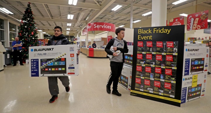 A shopper is pictured carrying a TV set out of a Tesco Extra store in Manchester. Notice the lack of crowds.