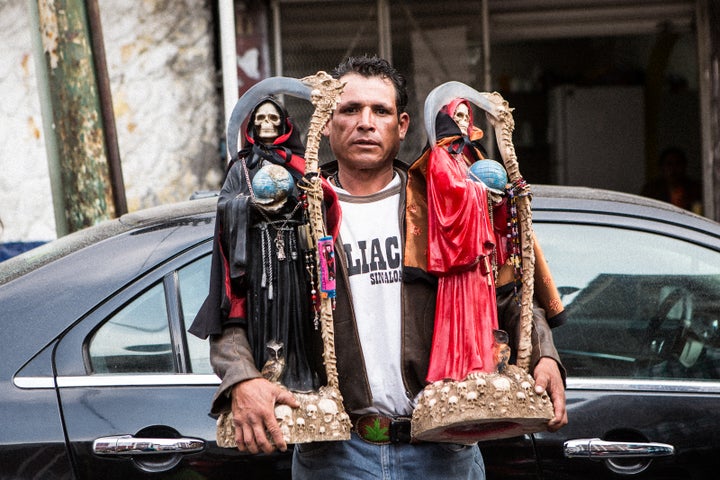 Devotee at Tepito shrine with his Santa Muertes of protection and passion