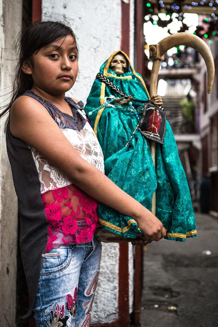<p>A young devotee at the Tepito shrine with her handcrafted Santa Muerte</p>