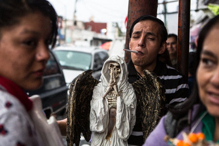 <p>A devotee with his Angel of Death at the Santa Muerte shrine in Tepito</p>