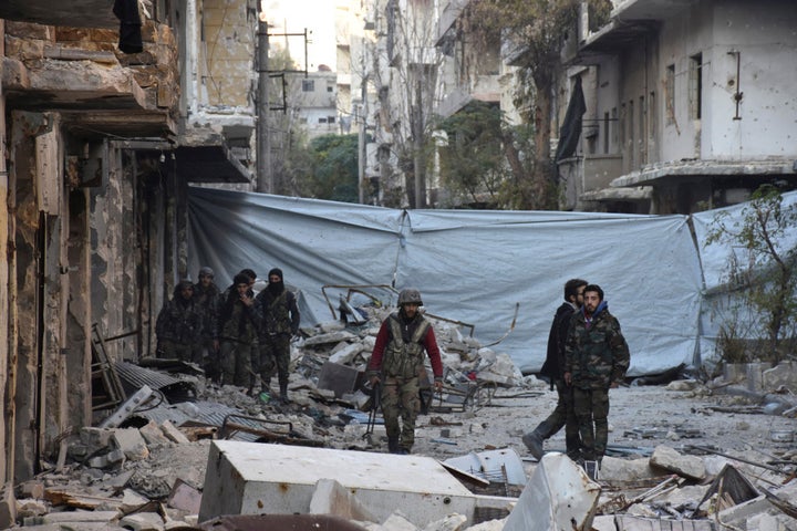 Syrian government soldiers walk amid rubble of damaged buildings, near a cloth used as a cover from snipers, after they took control of al-Sakhour neighborhood in Aleppo, Syria in this handout picture provided by SANA on November 28, 2016.