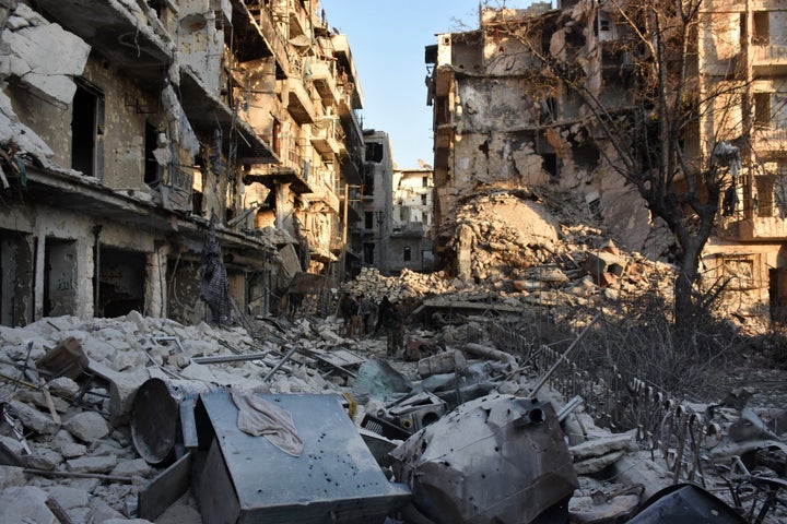 Syrian pro-government forces walk amidst heavy destruction in Aleppo's Bustan al-Basha neighbourhood on November 28, 2016, du