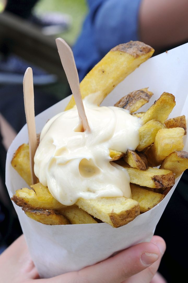 A cone of fries topped with mayonnaise.